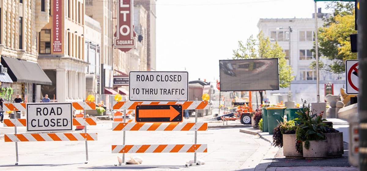 Road closure signs with construction occurring in background in downtown Aurora