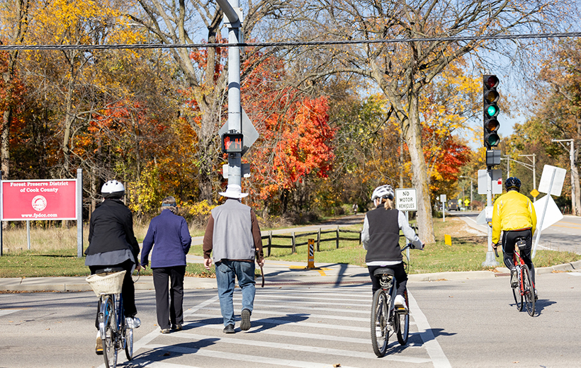 Pedestrians and bicyclists cross street at crosswalk.