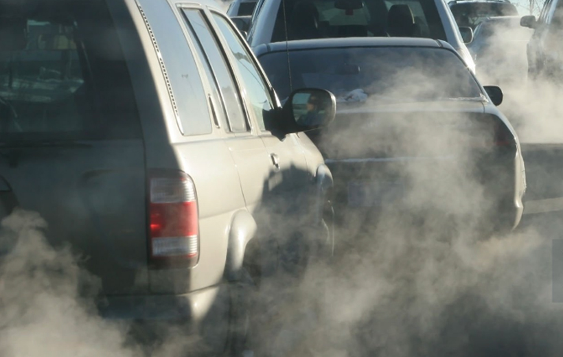 Image of vehicles at stop light with exhaust clouding up the air