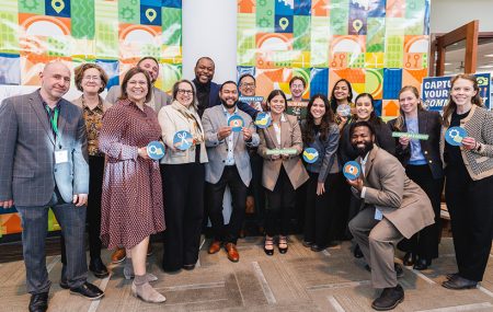 Photo of group of about 15 people posing standing together and holding commitment cards