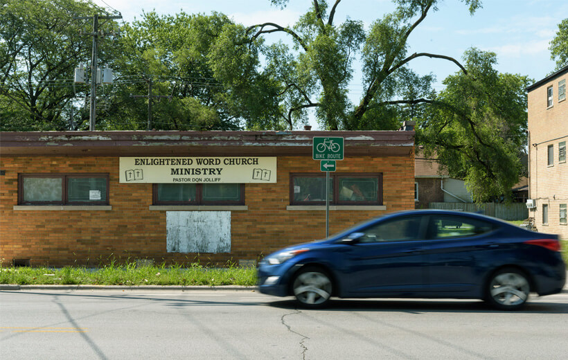 A blue car driving past an Enlightened Word Church Ministry