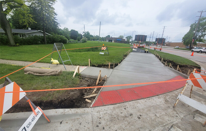 Sidewalk under construction with freshly installed ADA warning pads undergoing the drying process
