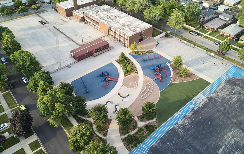 Vibrant playground nestled amidst greenery, a modern large two-story building, a running track, and a peaceful residential neighborhood.