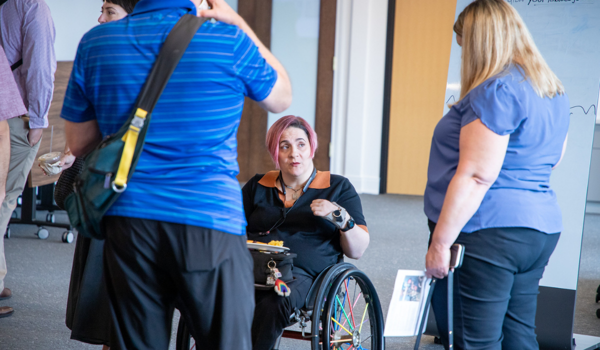 Women in wheelchair talks to another woman in a conference room