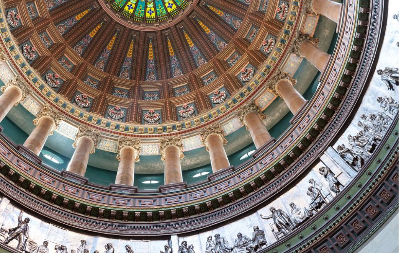 Looking up at dome of capitol building from insite. Pillars and lots of colorful, patterned designs.