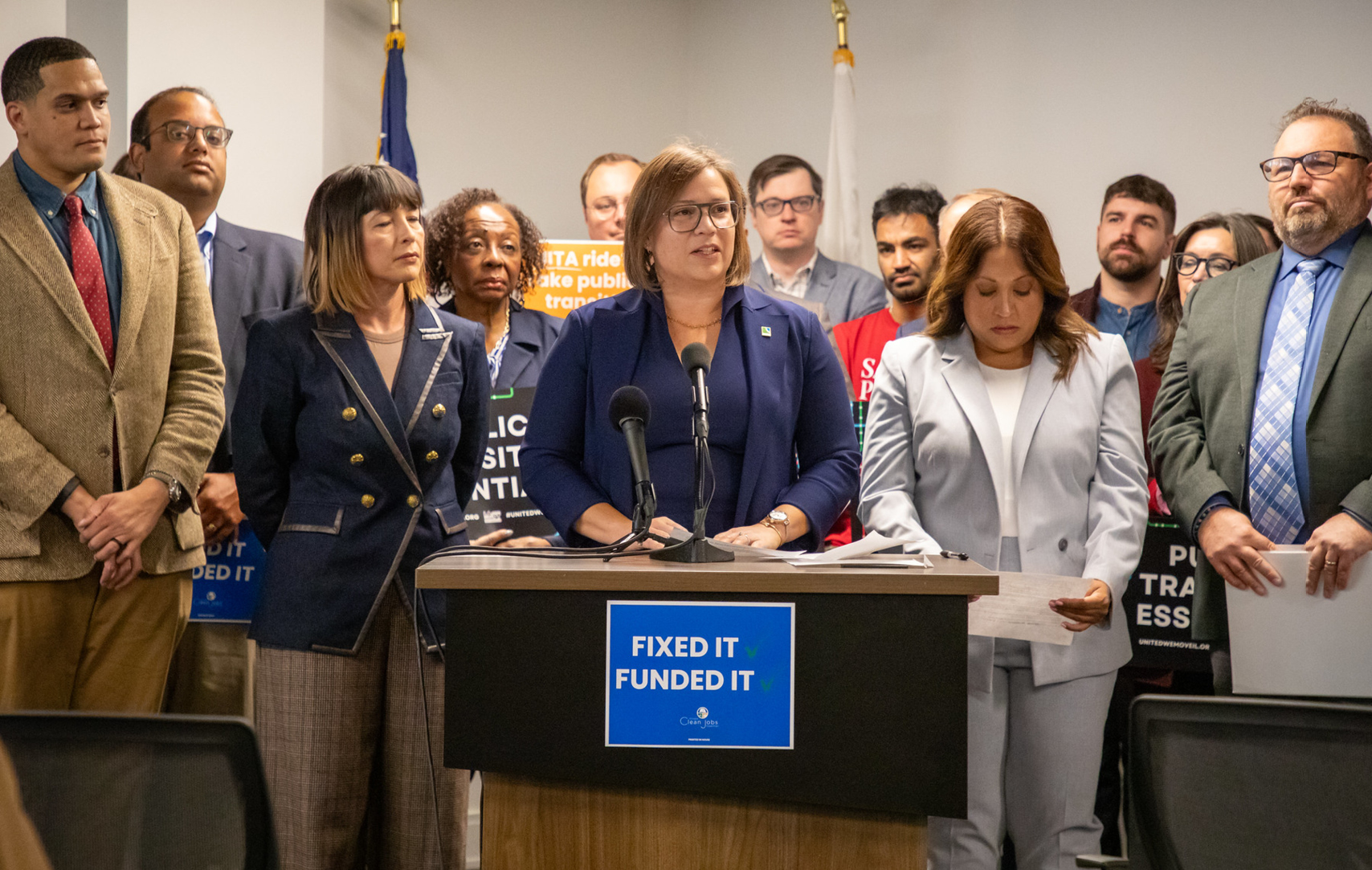 Erin Aleman addressing the press at a podium during a transit legislative victory press conference